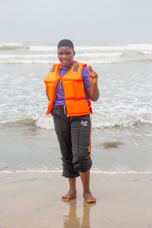A pupil in a life jacket standing in the surf