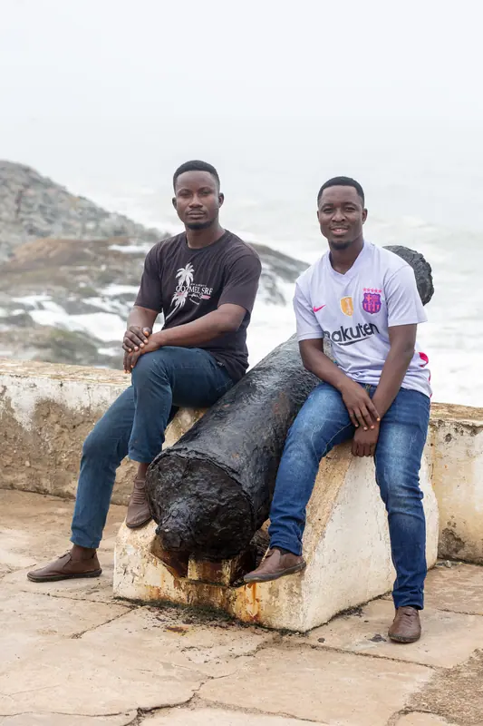 Two older pupils seated on a cannon overlooking the sea
