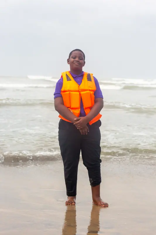 A pupil in a life jacket at the water's edge