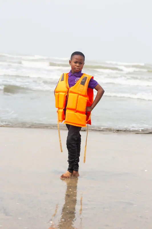 A pupil in a life jacket standing in the shallows