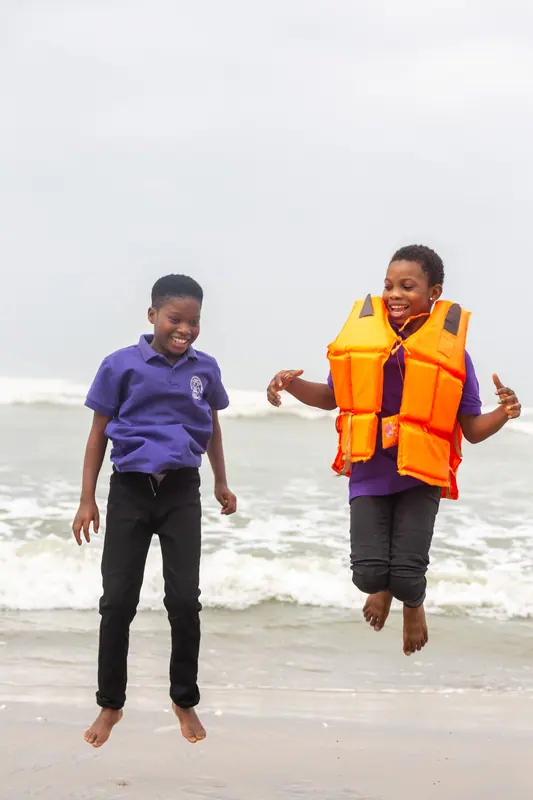 Two pupils jumping for the camera on the beach