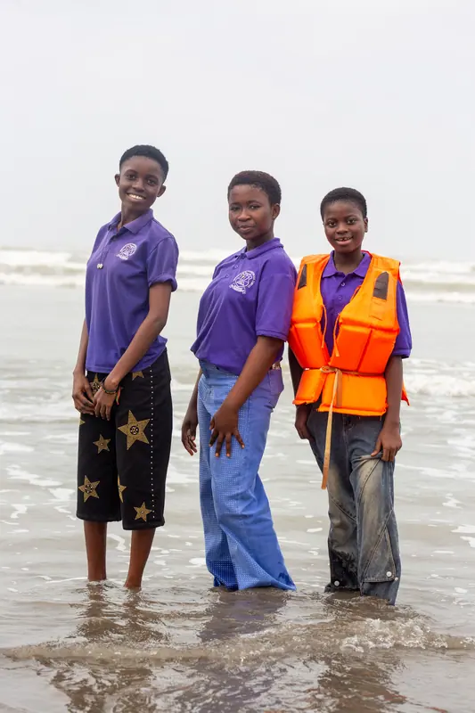 Three pupils standing in the surf