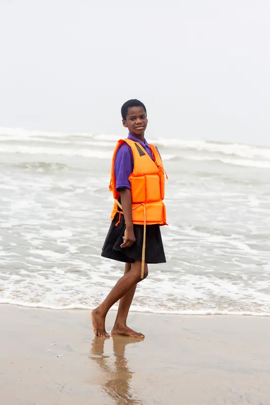 A pupil in a life jacket walking the shoreline