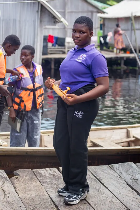 A pupil with a carved model canoe on the village jetty