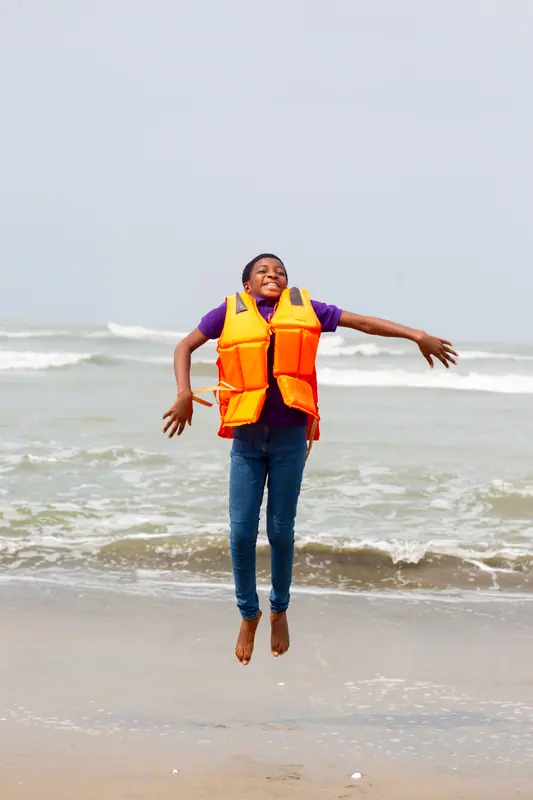 A pupil leaping with arms wide open on the beach